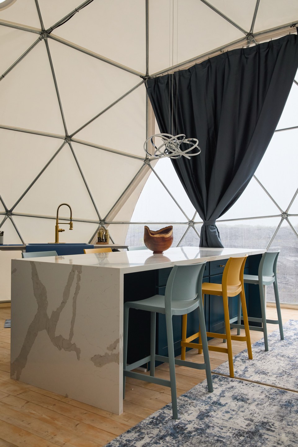 Interior styling at The Albizia: a pale stone counter and bar stools in a curved white space, the lava field beyond the window.